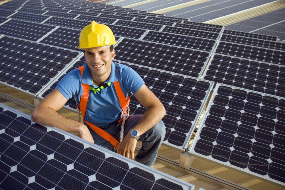 Solar contractor sitting next to solar panels array
