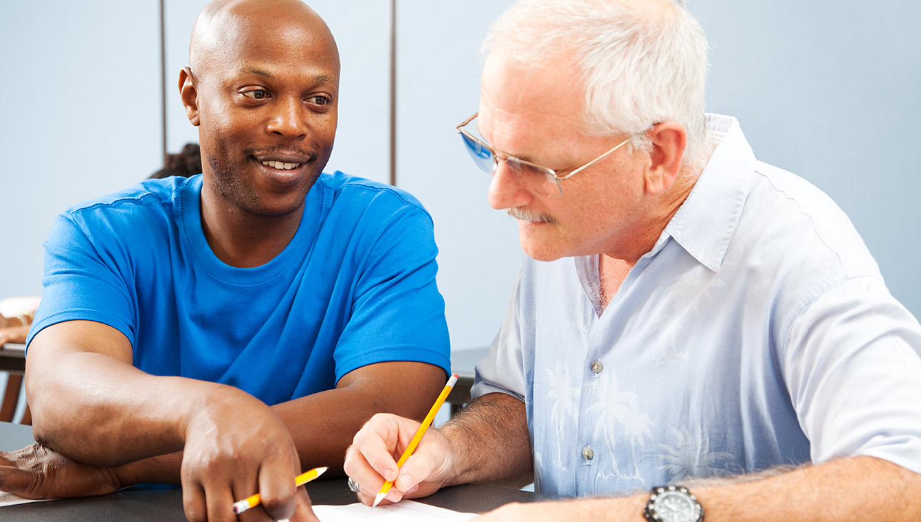 2 individuals checking papers and taking notes
