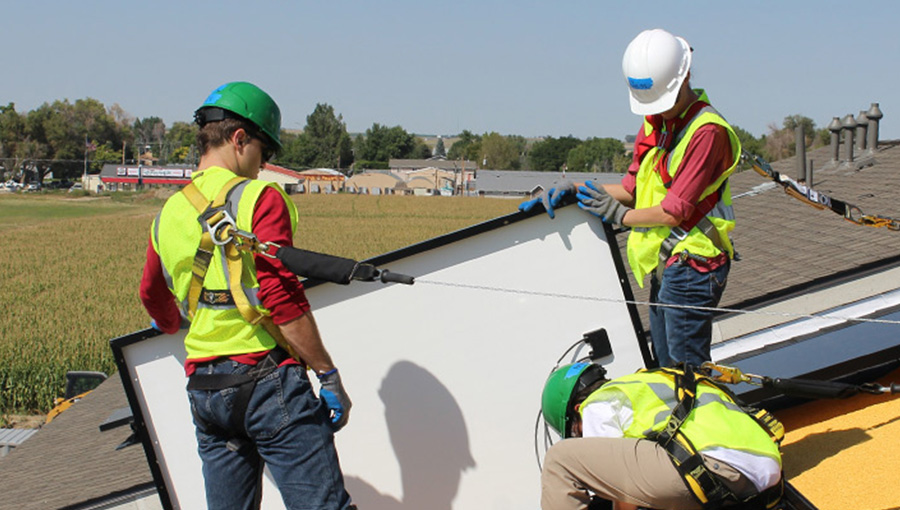 three workers installing pv on a roof